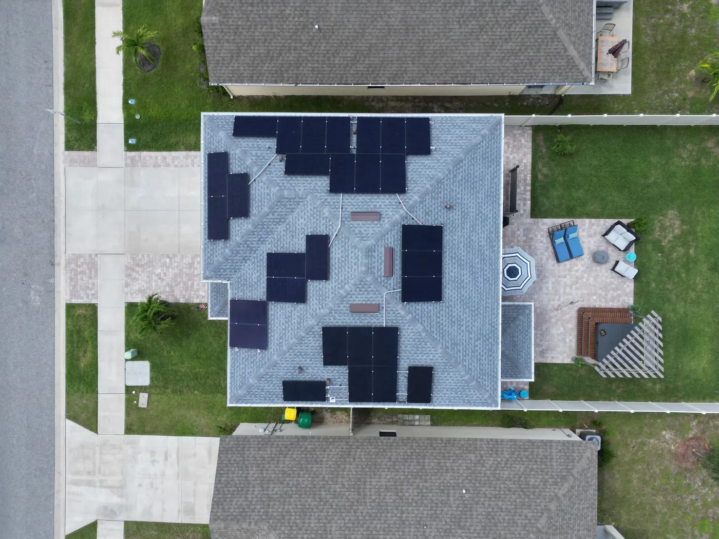 Top-down aerial view of all-black solar panels arranged across a complex roof
