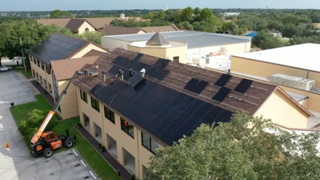 Solar arrays on the St. Luke’s shingle roofs with installers and a lift on Day 13