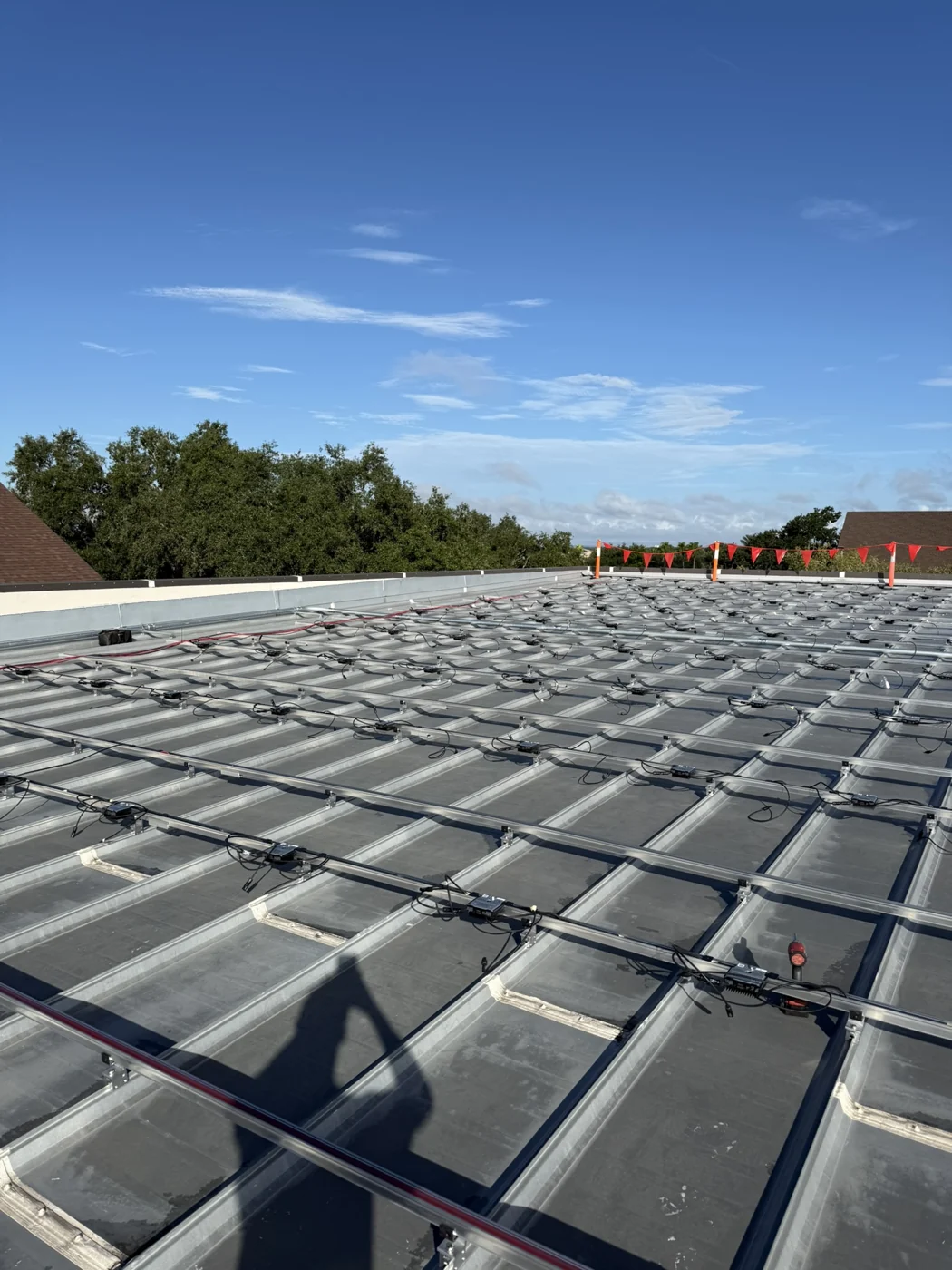 Mounting rails and wiring across the St. Luke’s metal roof on Day 18